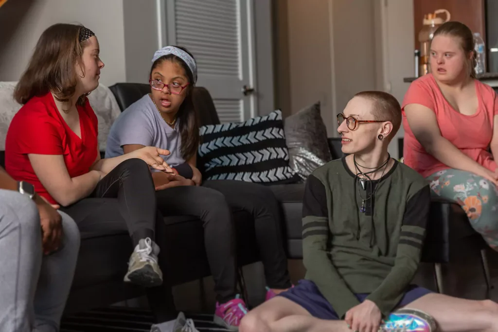 Diverse group of friends sitting on couch at home talking